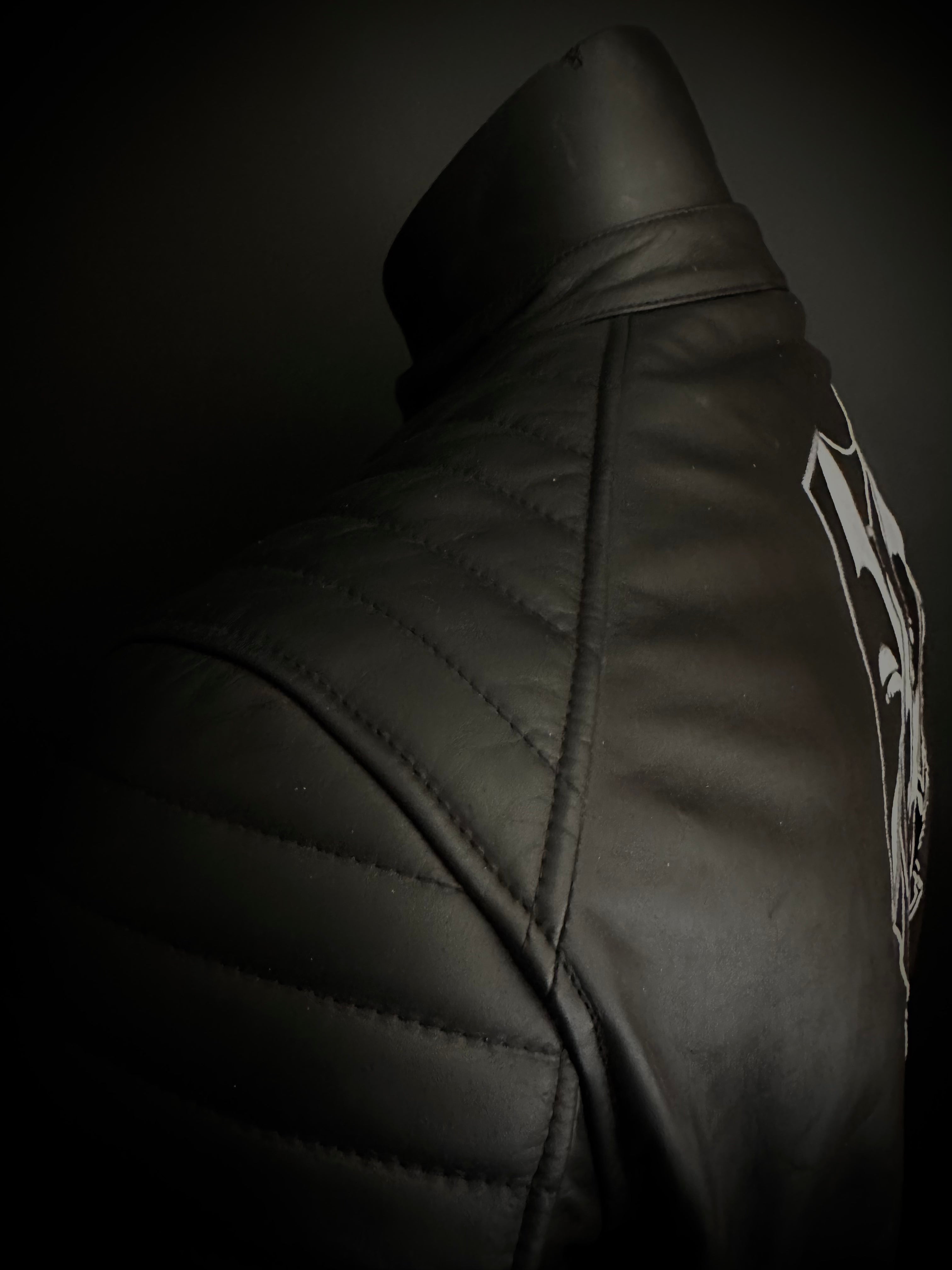 Shoulder stitching of black cafe racer style leather motorcycle jacket featuring precise stitches