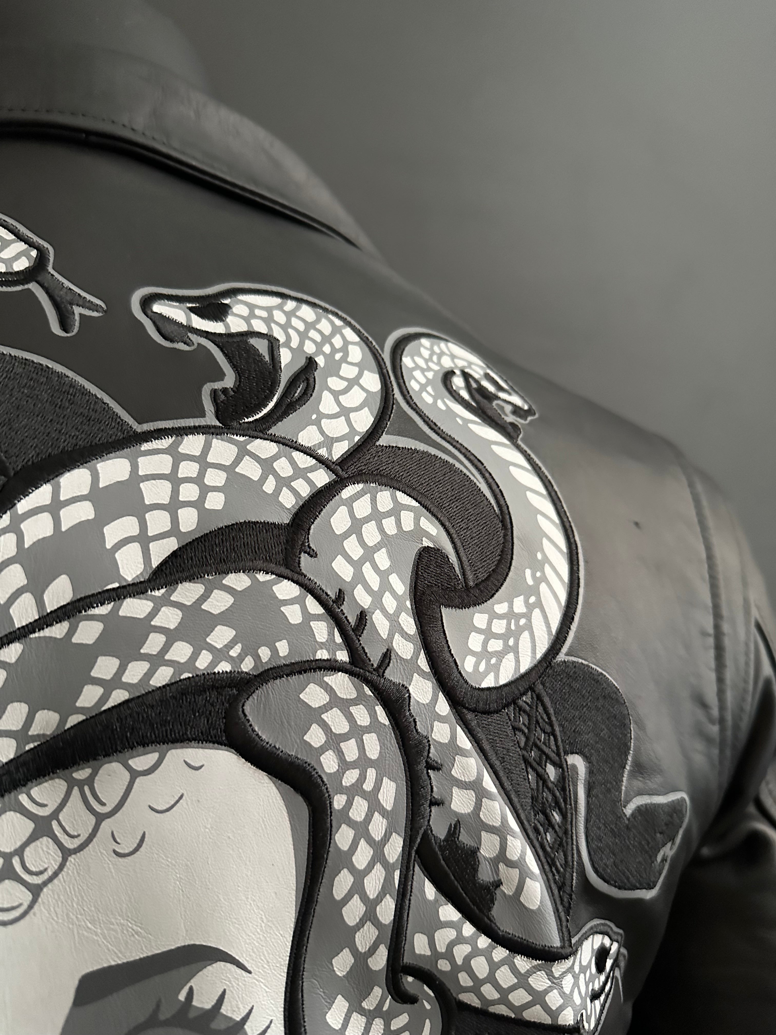 Top right corner of back of black motorcycle jacket with custom snake stitching and artwork